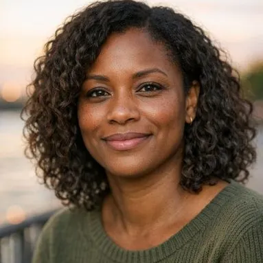 Woman in her late 30s with shoulder-length curls and warm brown eyes, soft smile